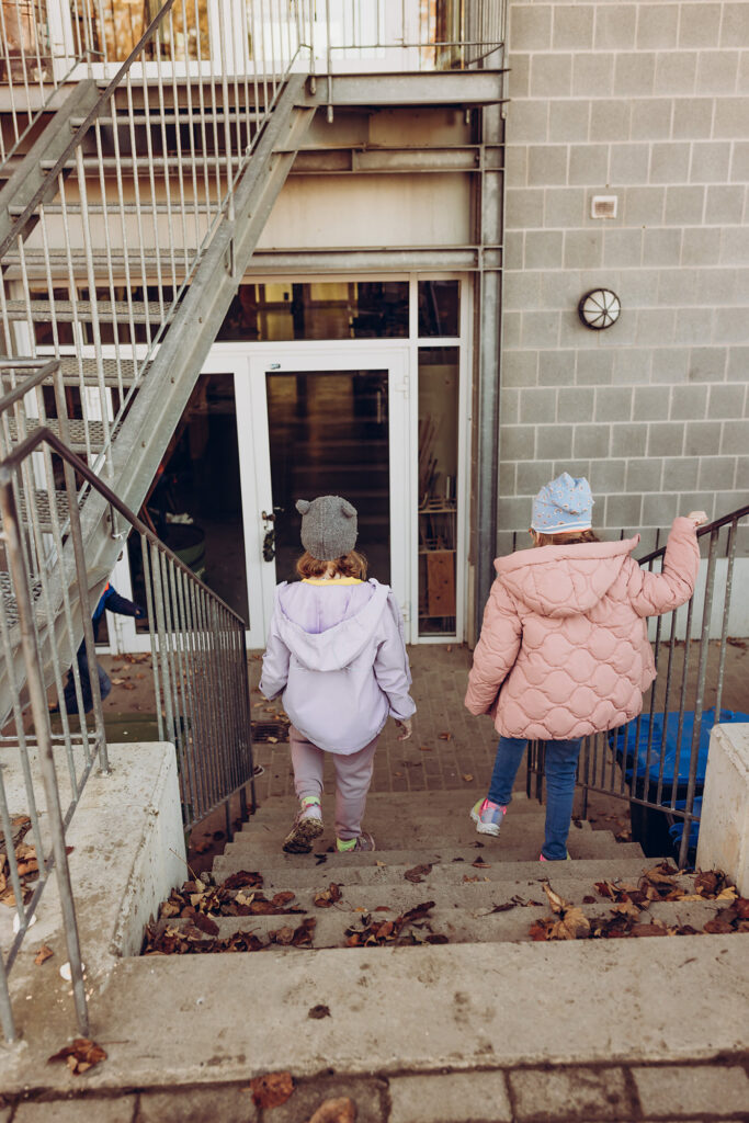 Kinder gehen gemeinsam die Treppe zum Schulgebäude hinauf