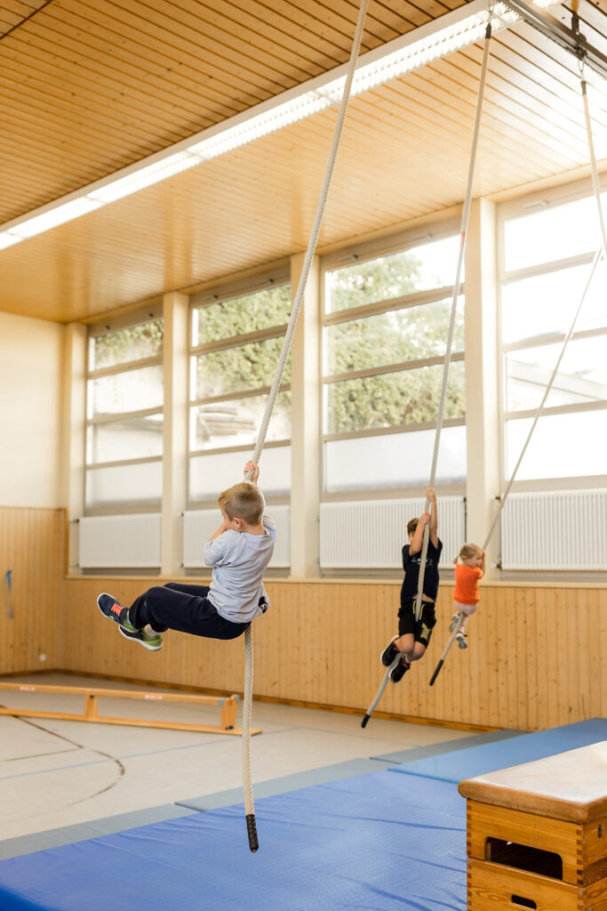Kind schwingt an Seilen in der Turnhalle