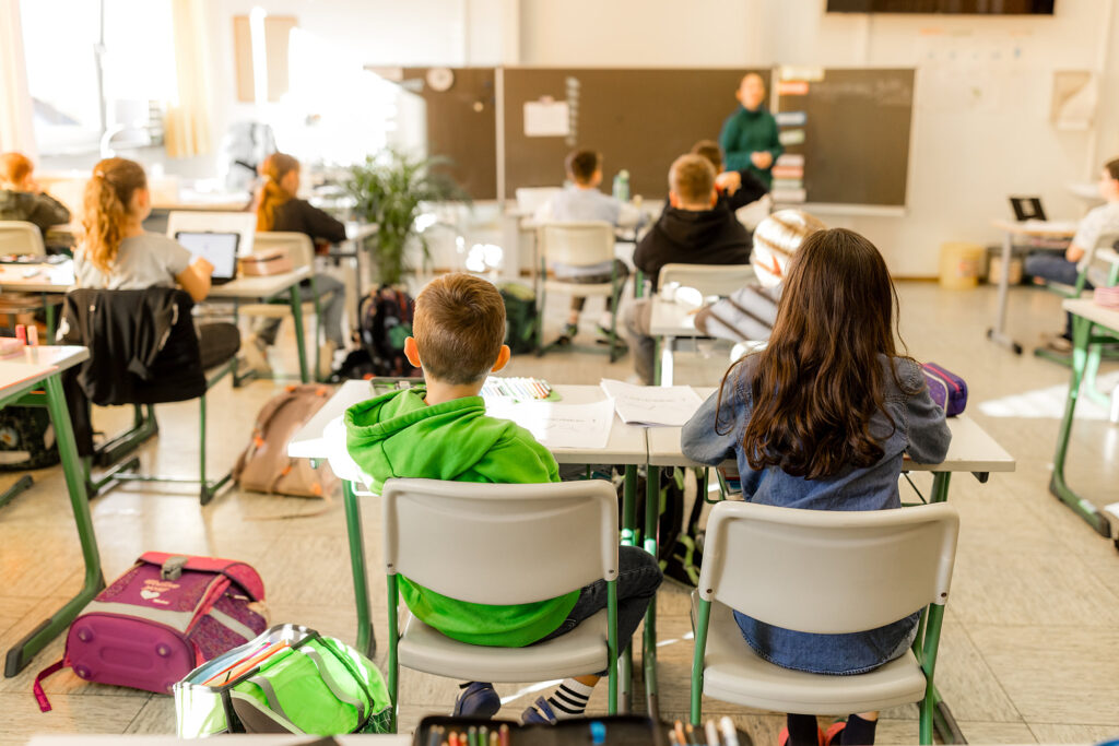 Kinder sitzen im Klassenzimmer und hören der Lehrerin zu