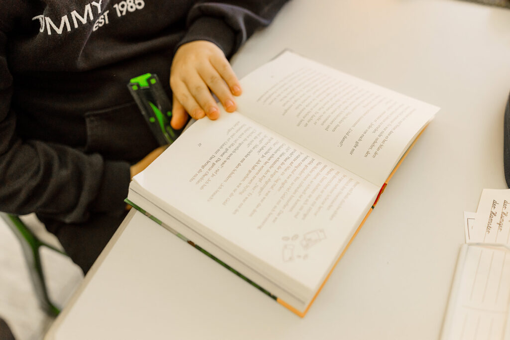 Kind liest in einem Buch am Tisch