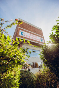 Schulgebäude mit Sonnenlicht und Pflanzen im Vordergrund