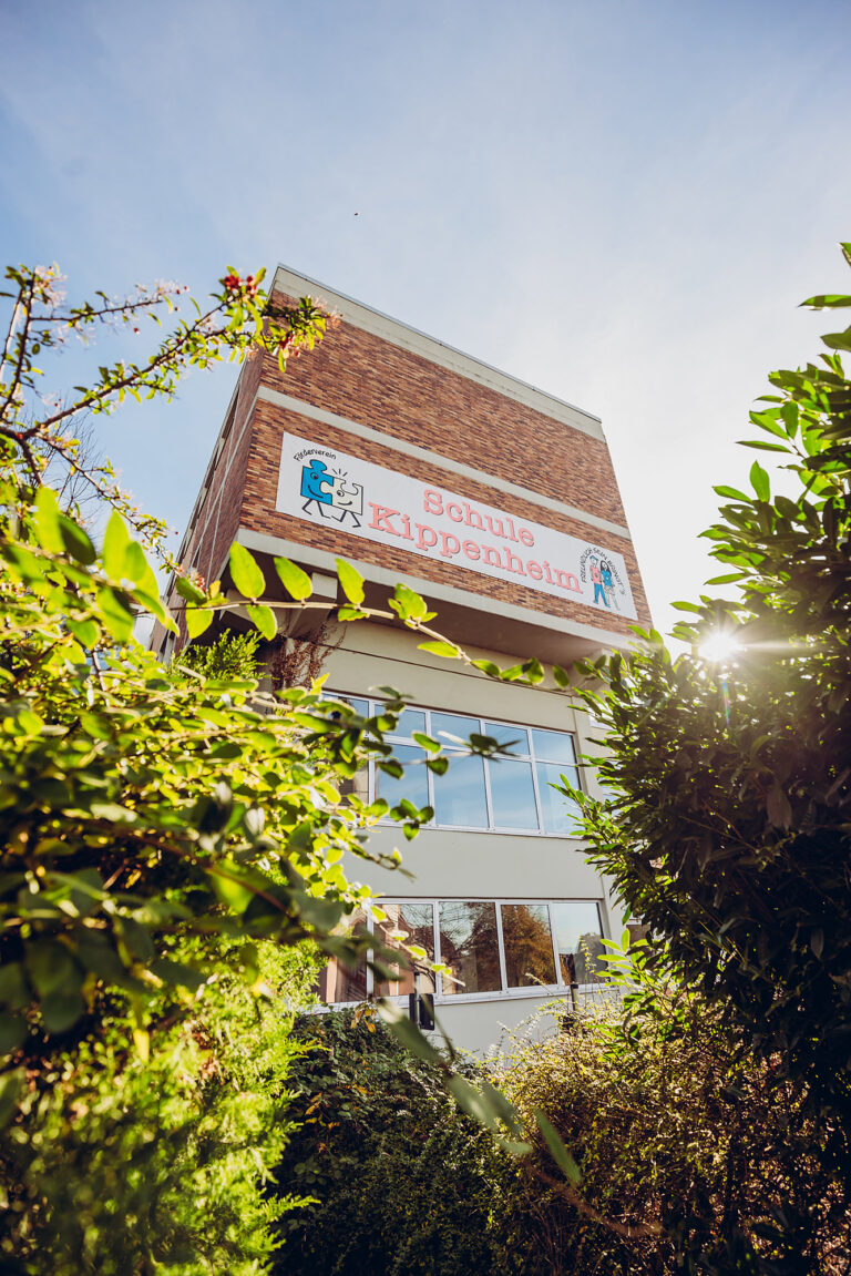 Schulgebäude mit Sonnenlicht und Pflanzen im Vordergrund