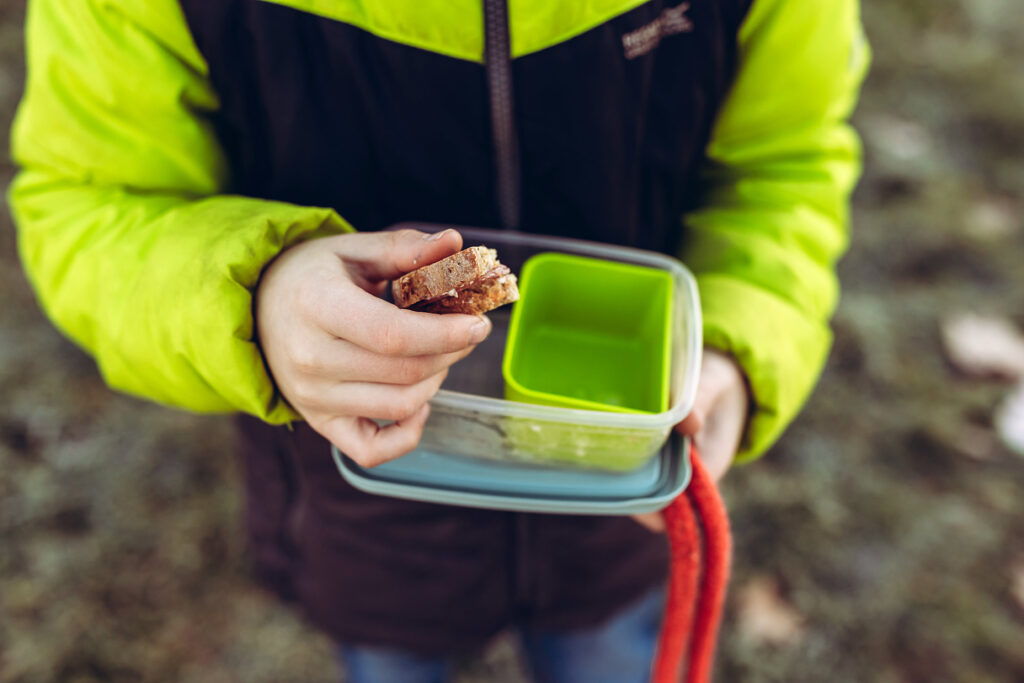 Kind hält eine Brotdose mit Essen in der Hand