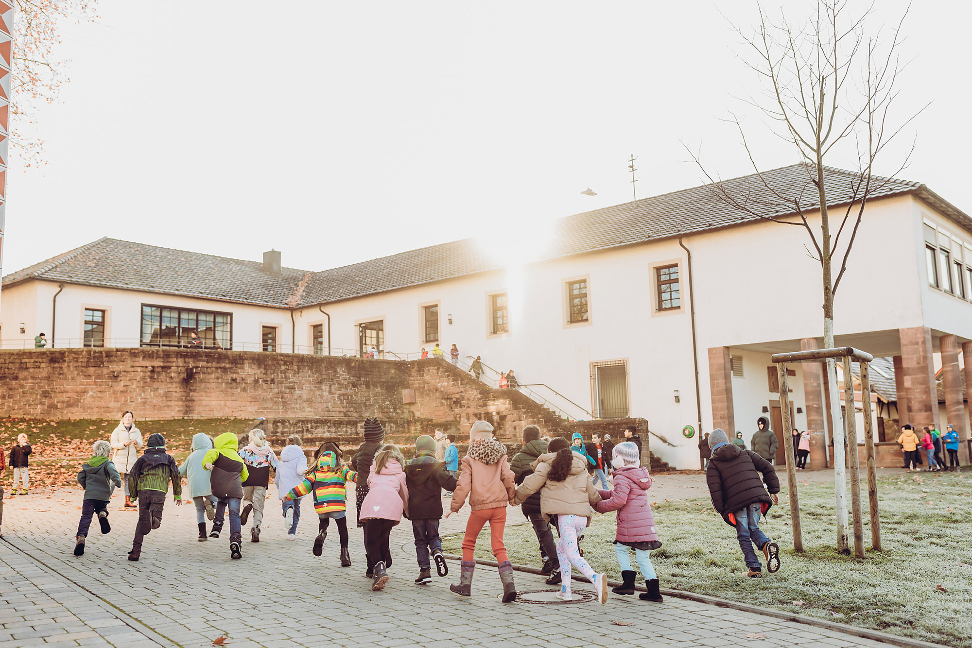 Kinder bewegen sich gemeinsam auf dem Schulhof vor dem Schulgebäude