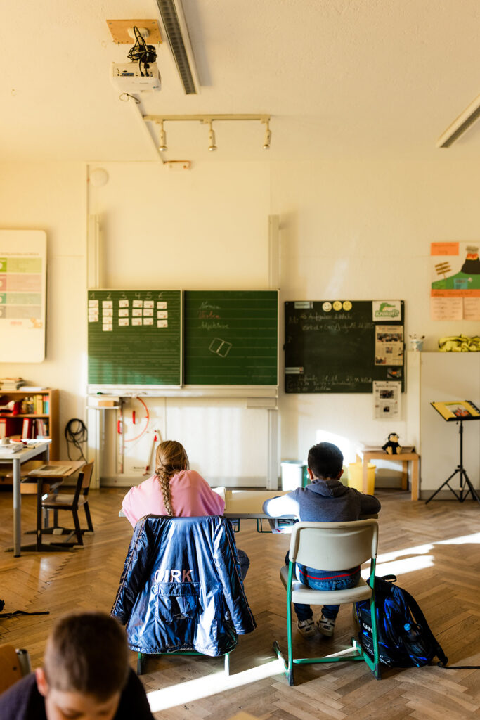 Kinder sitzen im Klassenzimmer und arbeiten an ihren Plätzen