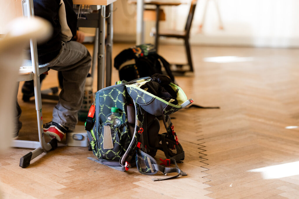 Schulranzen stehen neben Tischen im Klassenzimmer