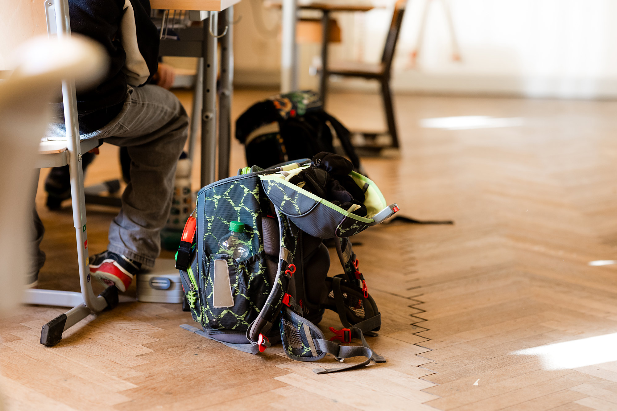 Schulranzen stehen neben Tischen im Klassenzimmer