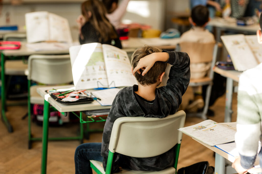 Kind liest ein Buch am Platz im Klassenzimmer