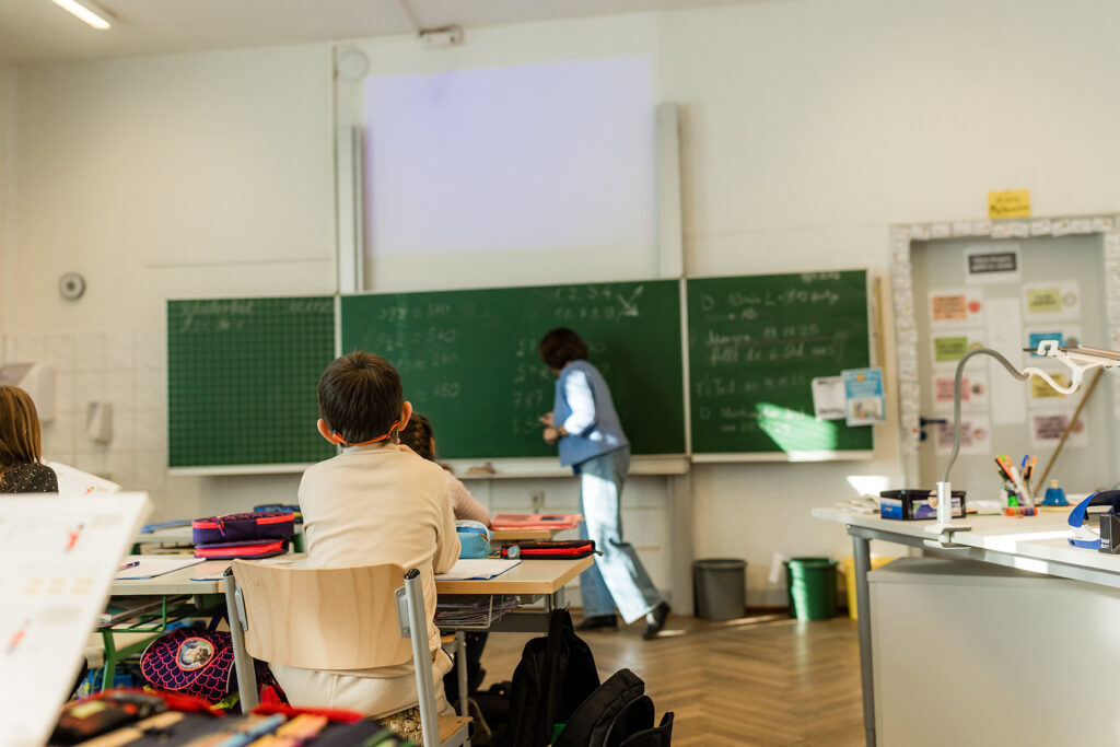 Lehrerin erklärt etwas an der Tafel im Klassenzimmer