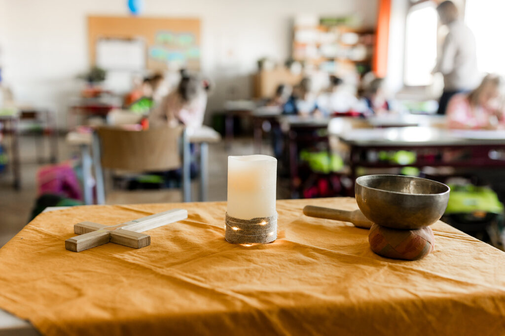 Tisch mit Materialien für Religionsunterricht im Vordergrund, Klassenzimmer im Hintergrund